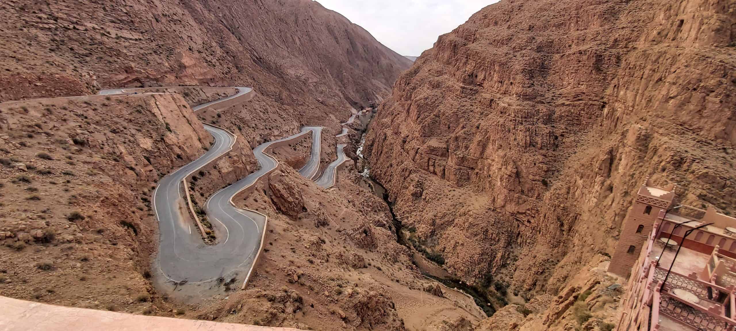 Una sinuosa carretera de montaña se curva bruscamente a través de un paisaje de cañón rocoso y árido con acantilados escarpados a ambos lados.
